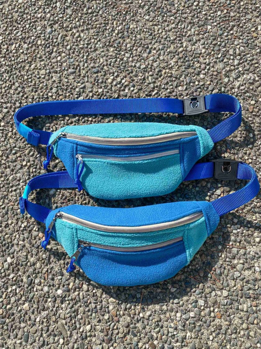 two blue fanny bags sitting on the ground.