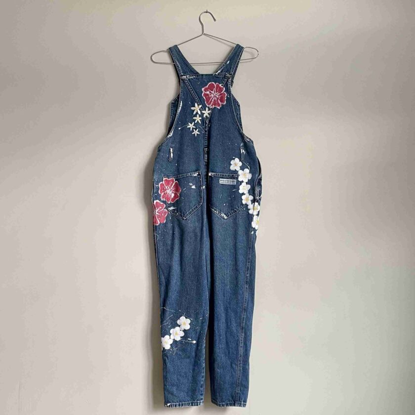 a denim jumpsuit hanging on a wall.
