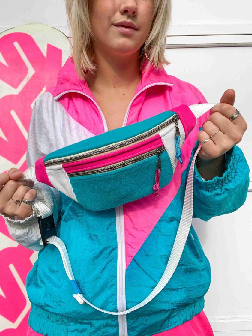 a woman in a pink and blue jacket holding a blue and white purse.