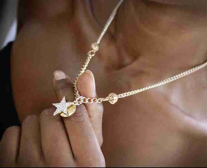 a woman holding a star necklace in her hand.