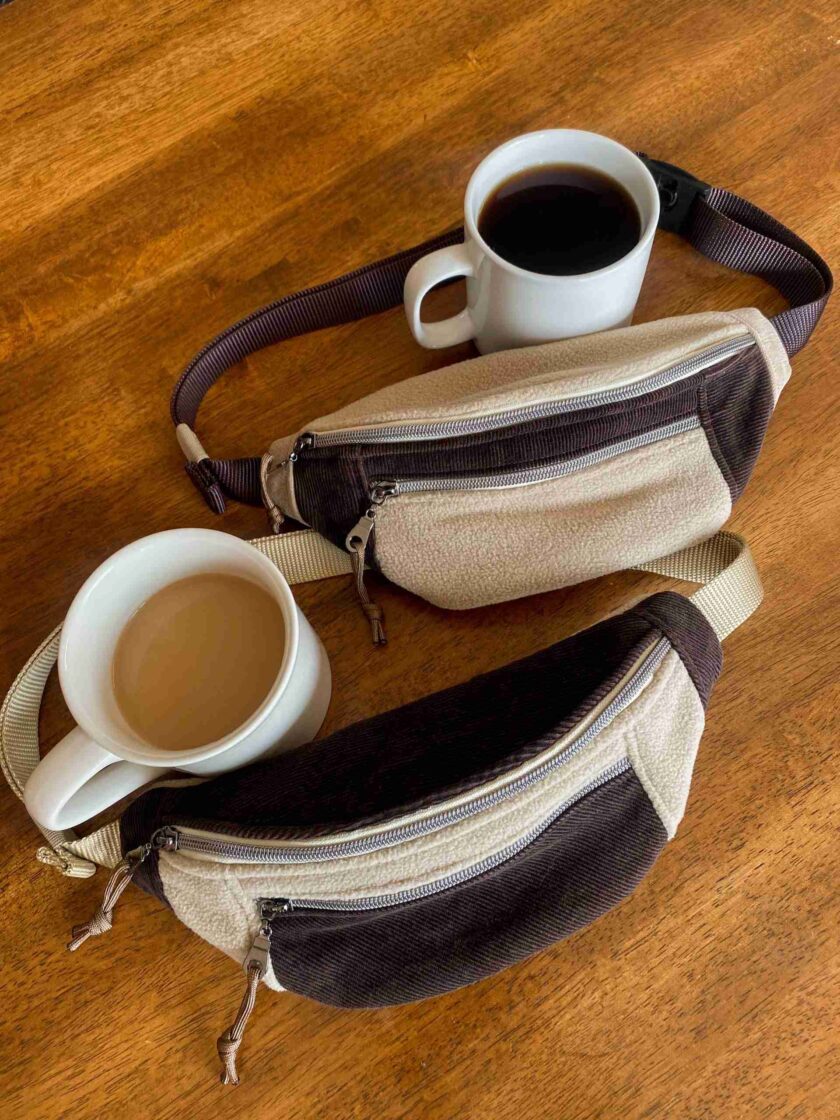 a cup of coffee and a purse on a wooden table.