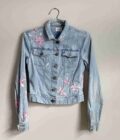 a denim jacket with pink flowers on it.