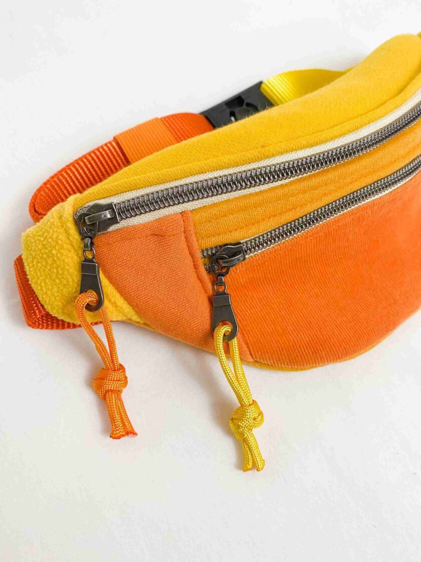 a yellow and orange fanny bag on a white surface.
