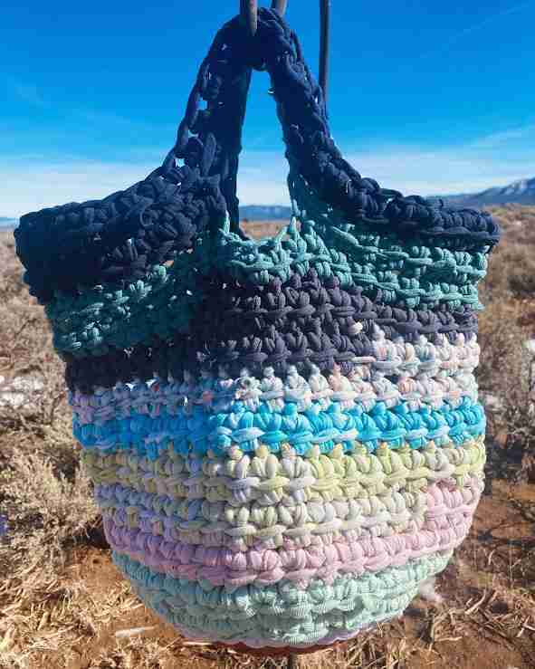 a multicolored crocheted bag hanging from a hook.