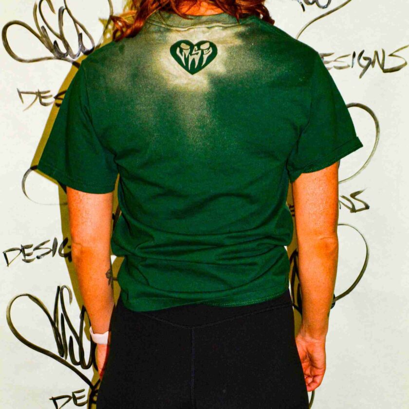 a woman wearing a green shirt with a heart on it.