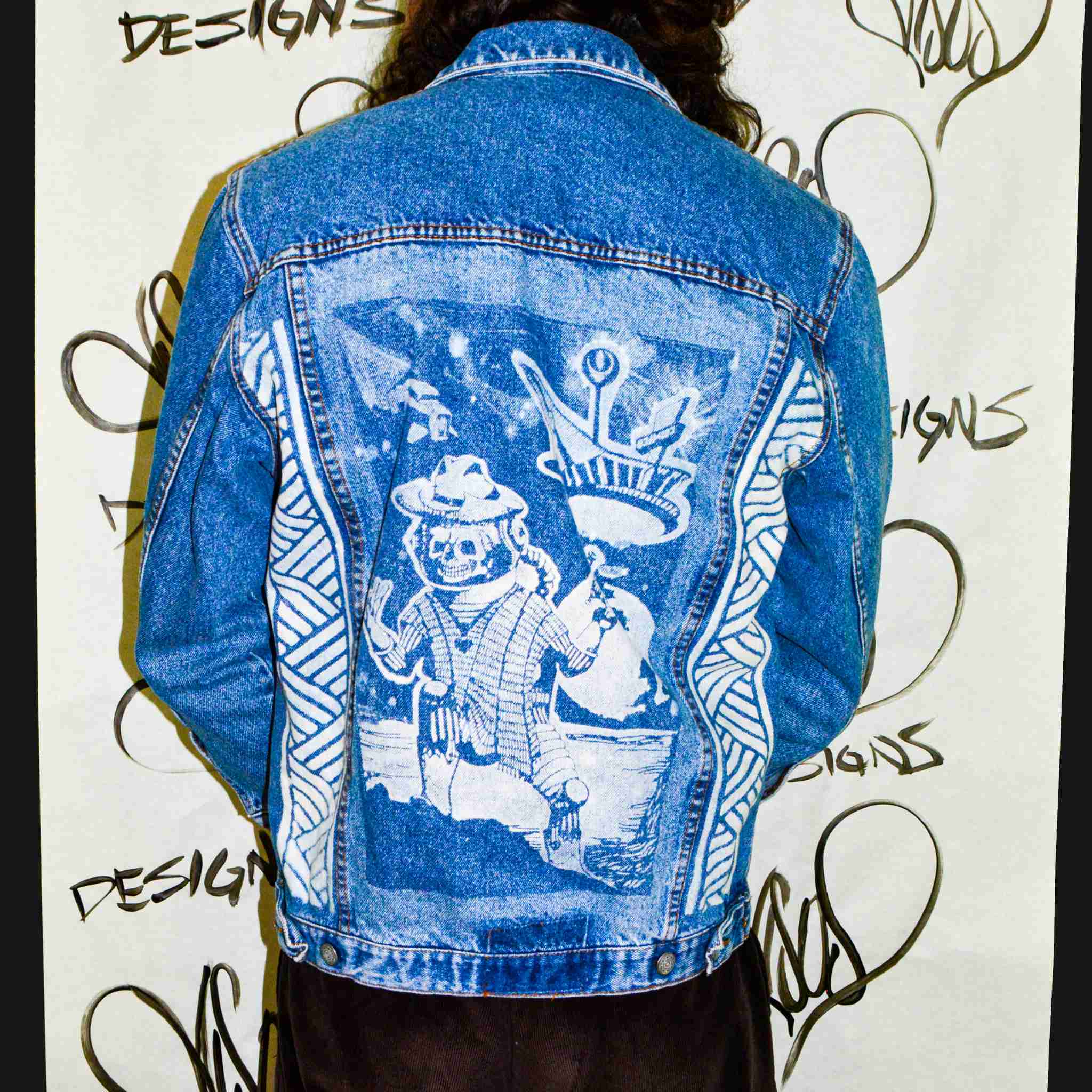a person wearing a jean jacket with a drawing on it.