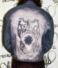a man wearing a jean jacket with a skull on it.