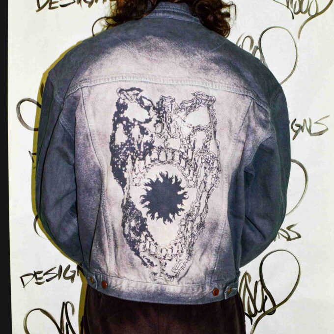 a man wearing a jean jacket with a skull on it.
