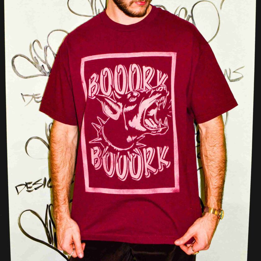 a man standing in front of a wall with a book book t - shirt on.