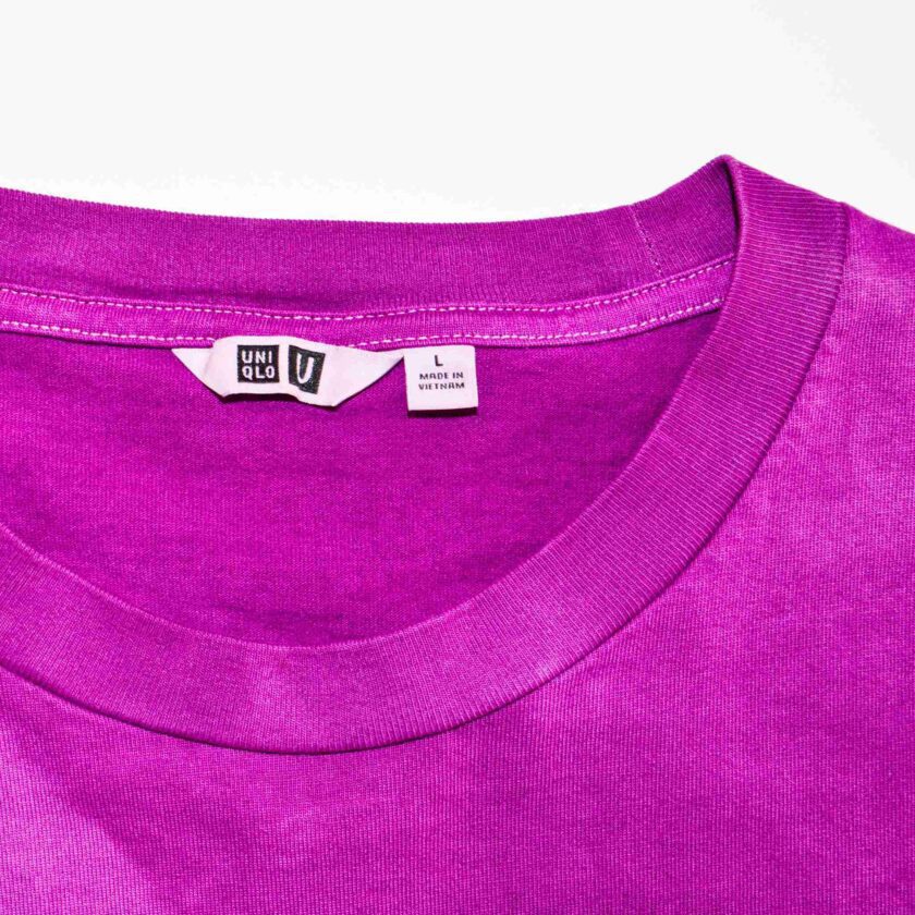 a close up of a purple shirt with a tag on it.