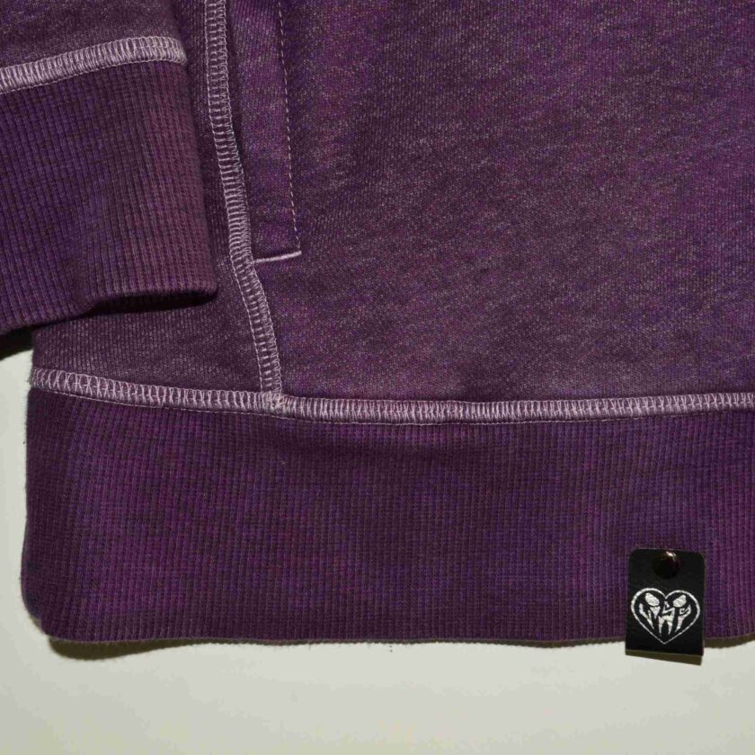 a close up of a purple shirt with a tag on it.