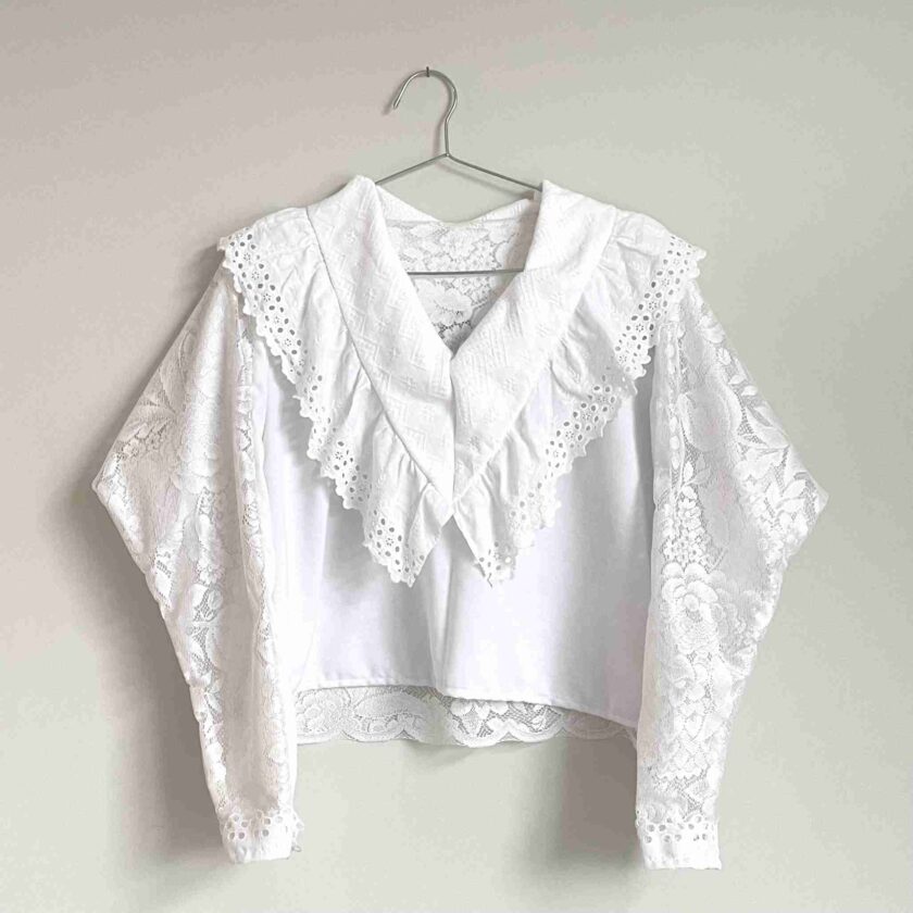 a white blouse hanging on a hanger.