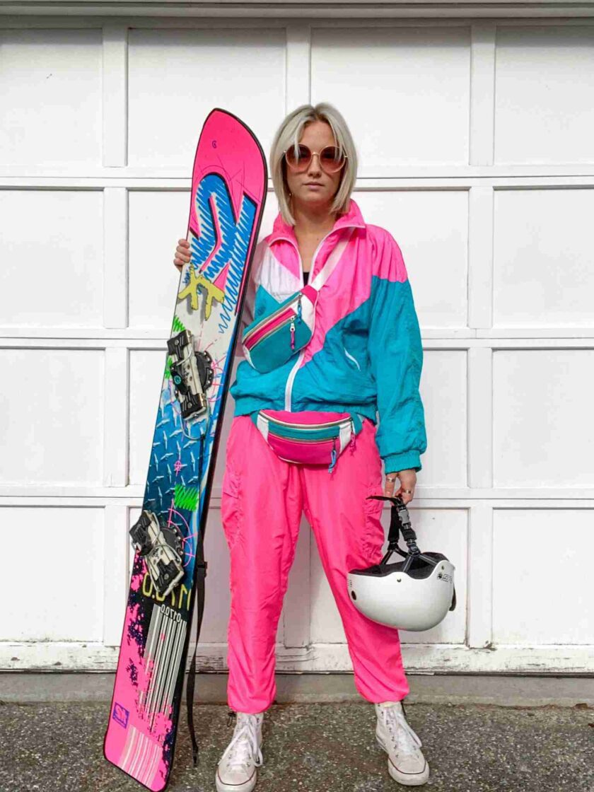 a woman in a pink snow suit holding a snowboard.
