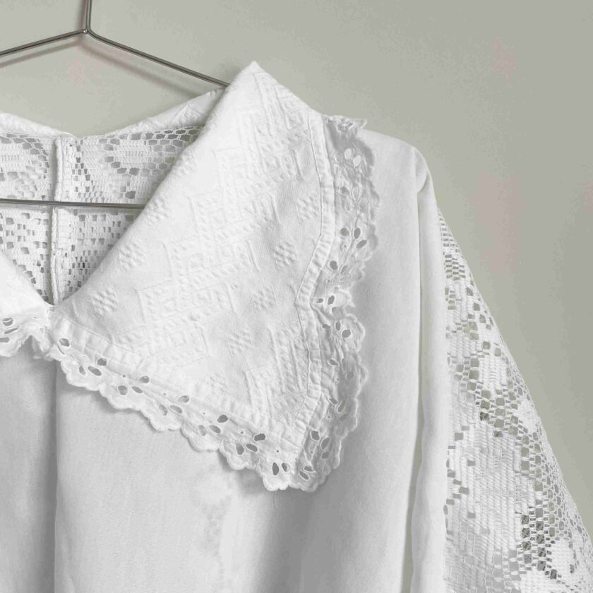 a white blouse hanging on a clothes rack.