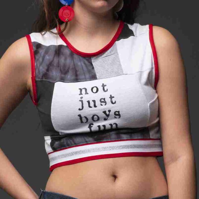 a woman wearing a crop top with the words not just boys fun on it.