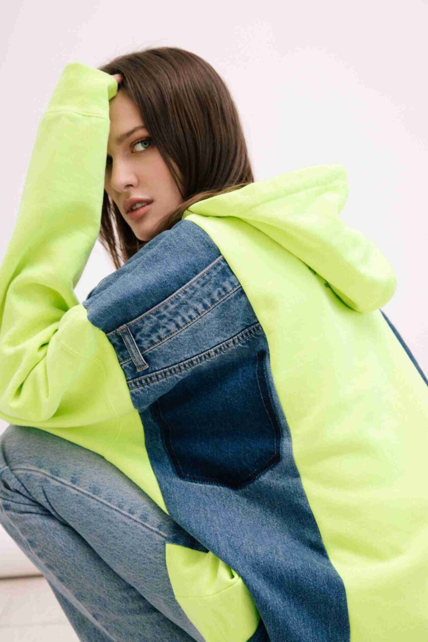 a woman in a yellow and blue jacket and jeans.