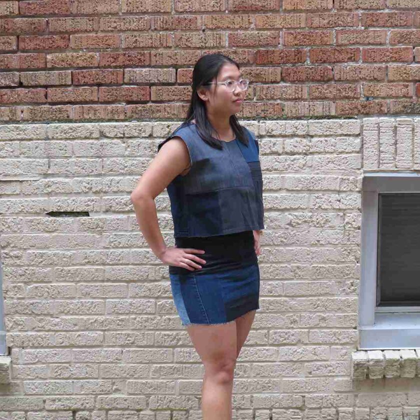 a woman standing in front of a brick wall.