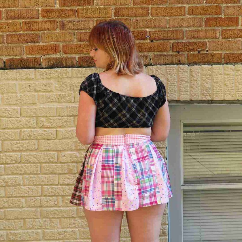 a woman standing in front of a brick wall.