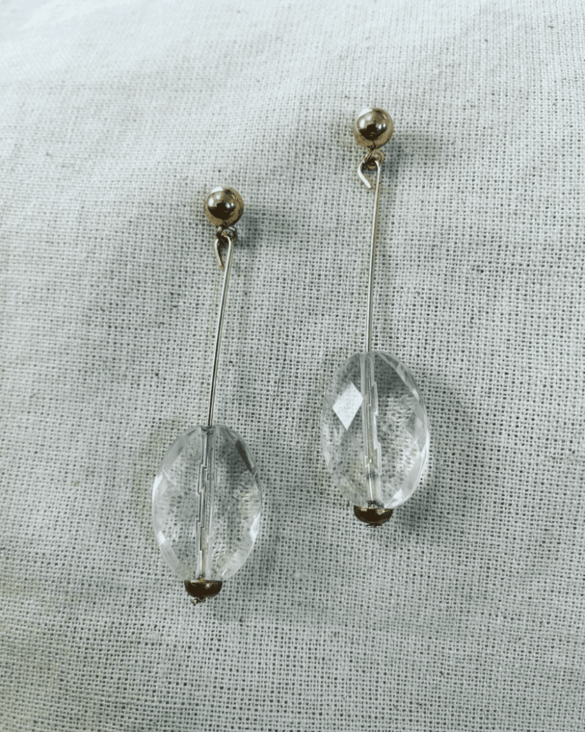 a pair of clear crystal earrings on a white cloth.