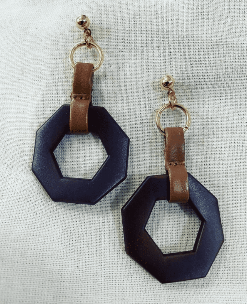 a pair of black and brown earrings on a white cloth.
