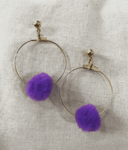 a pair of hoop earrings with purple pom poms.
