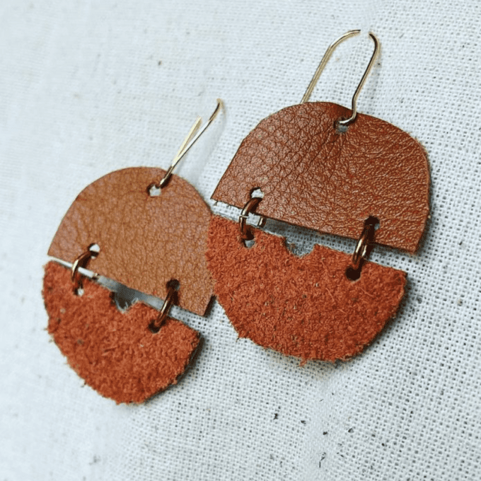 a pair of brown and tan leather earrings.