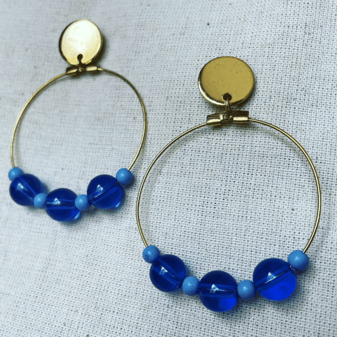 a pair of hoop earrings with blue beads.