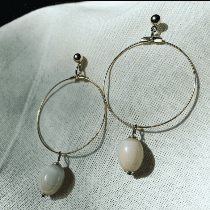 a pair of gold hoop earrings with pink beads.