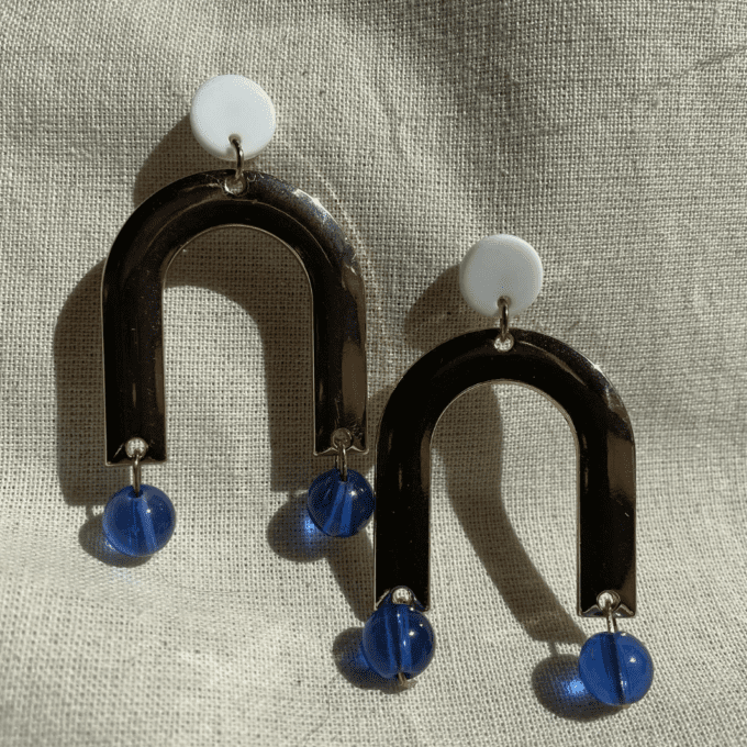 a pair of blue and white earrings sitting on top of a white cloth.