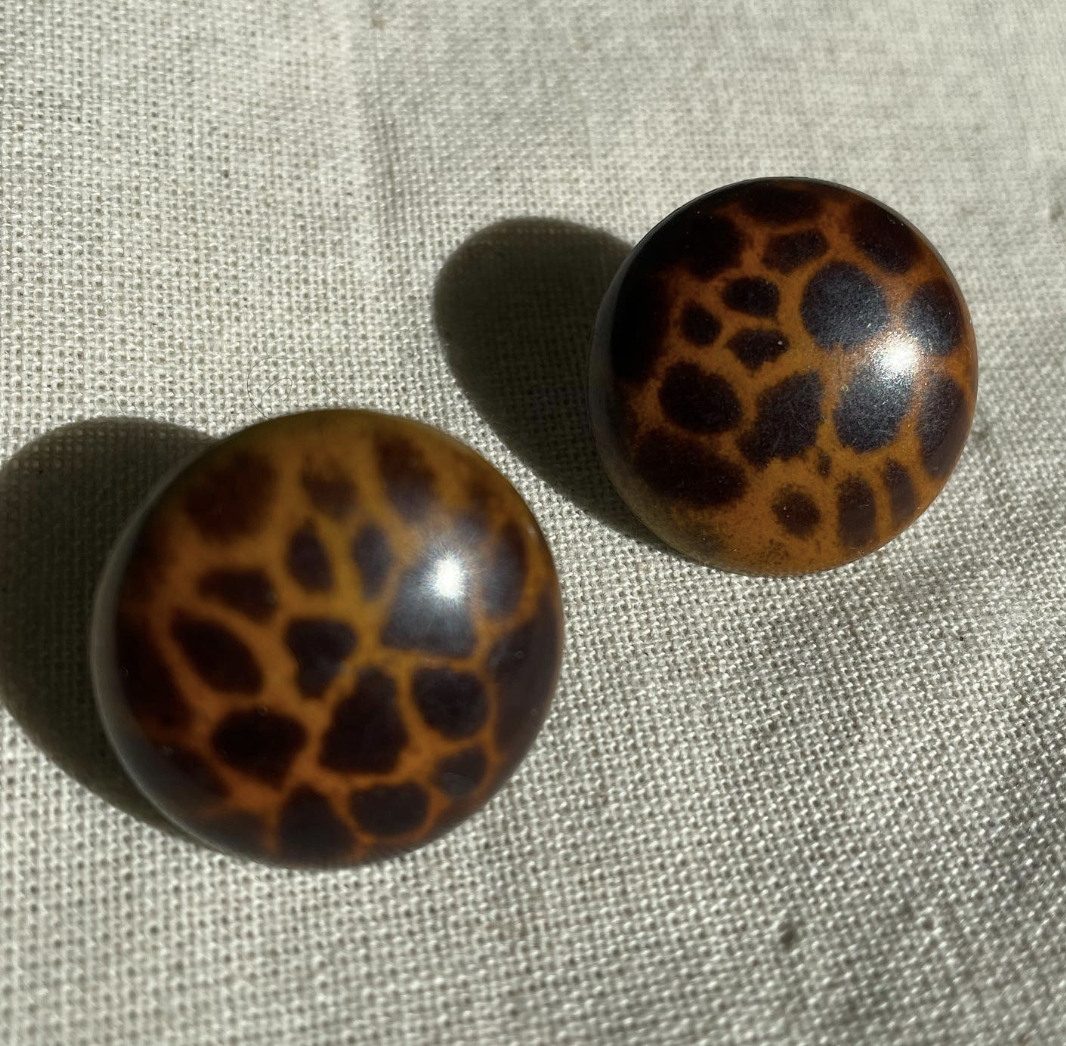 two brown and black balls sitting on top of a white cloth.
