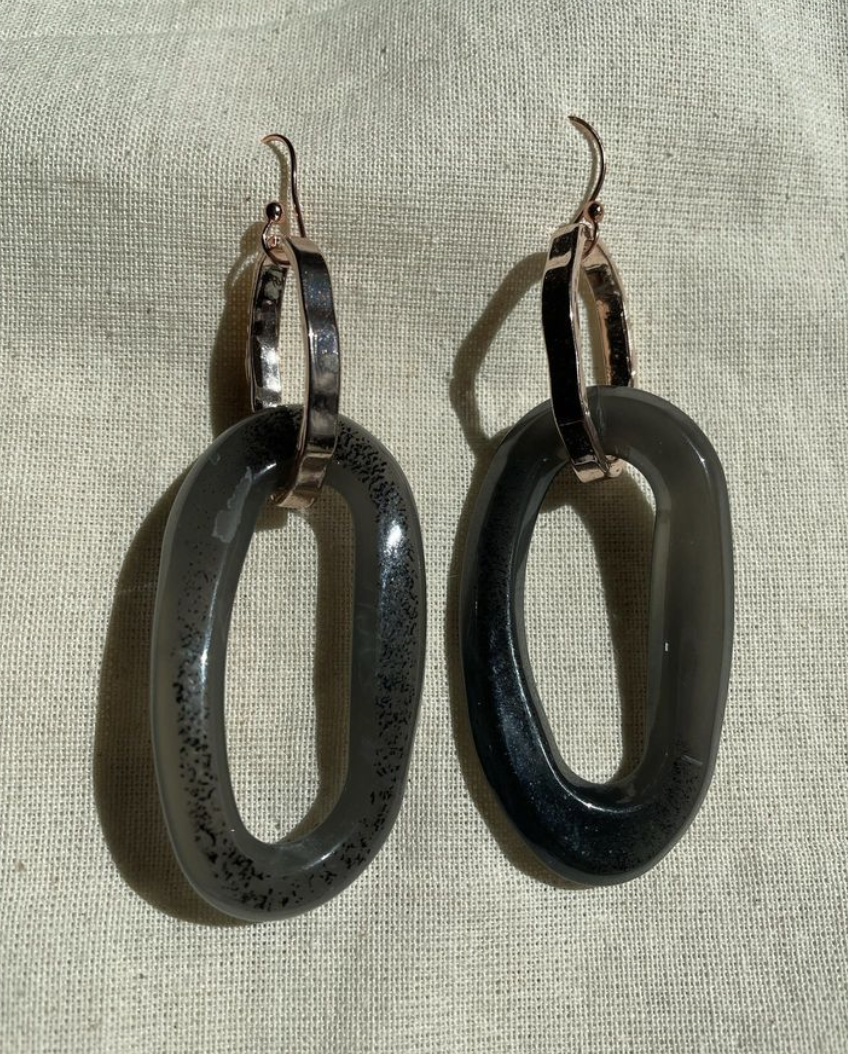a pair of black and silver earrings sitting on top of a white cloth.