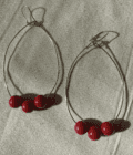 a pair of hoop earrings with red beads.