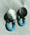 a pair of blue and gold earrings on a white cloth.