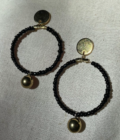 A pair of Black beaded gold drop hoop earrings.