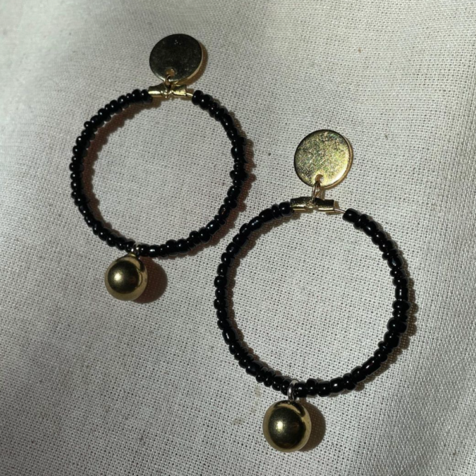 A pair of Black beaded gold drop hoop earrings.