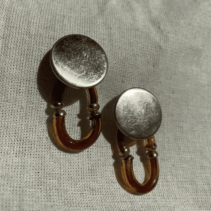 a close up of a pair of earrings on a cloth.