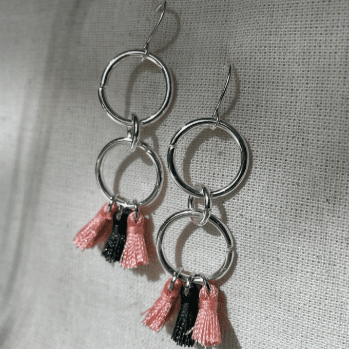 a pair of earrings with tassels hanging from them.