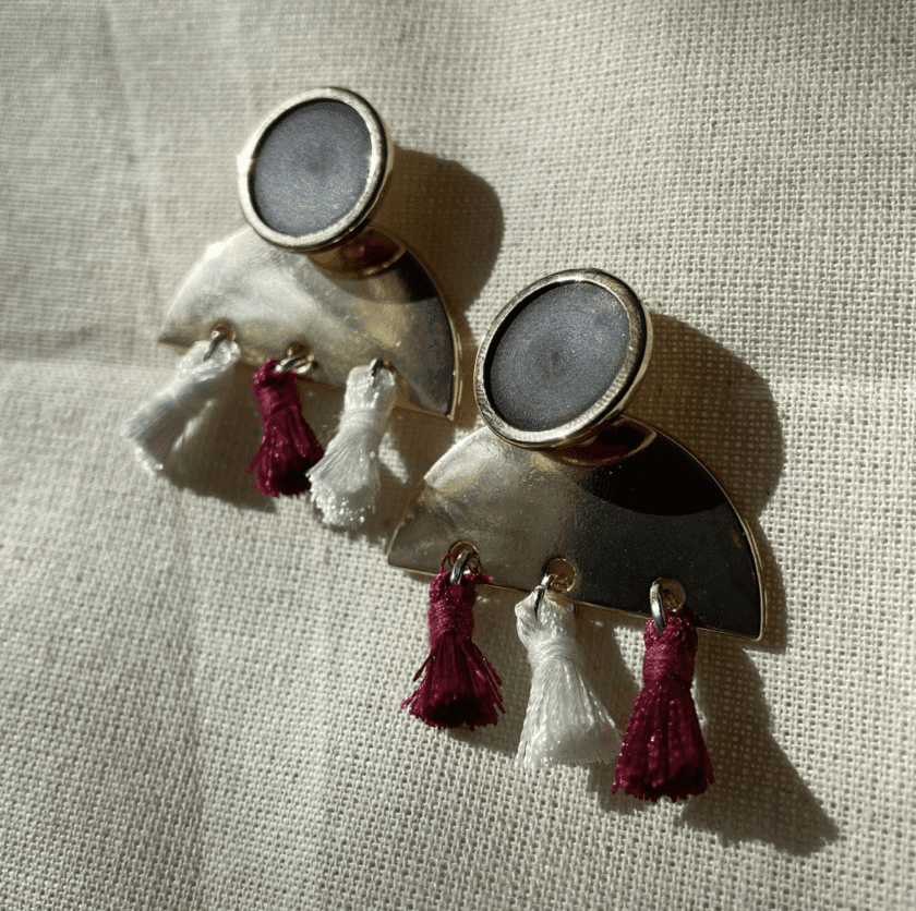 a pair of earrings with tassels on a white surface.