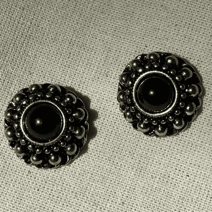 a pair of black and silver buttons on a white cloth.