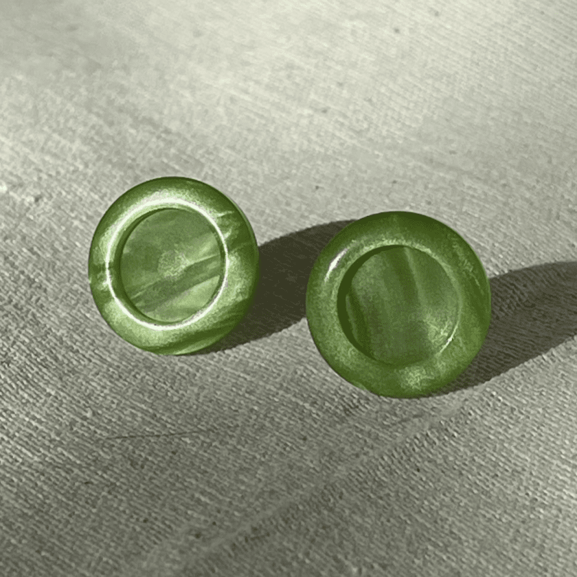 a pair of green buttons sitting on top of a table.