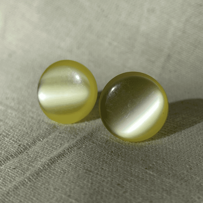 a pair of yellow pearls sitting on top of a white cloth.