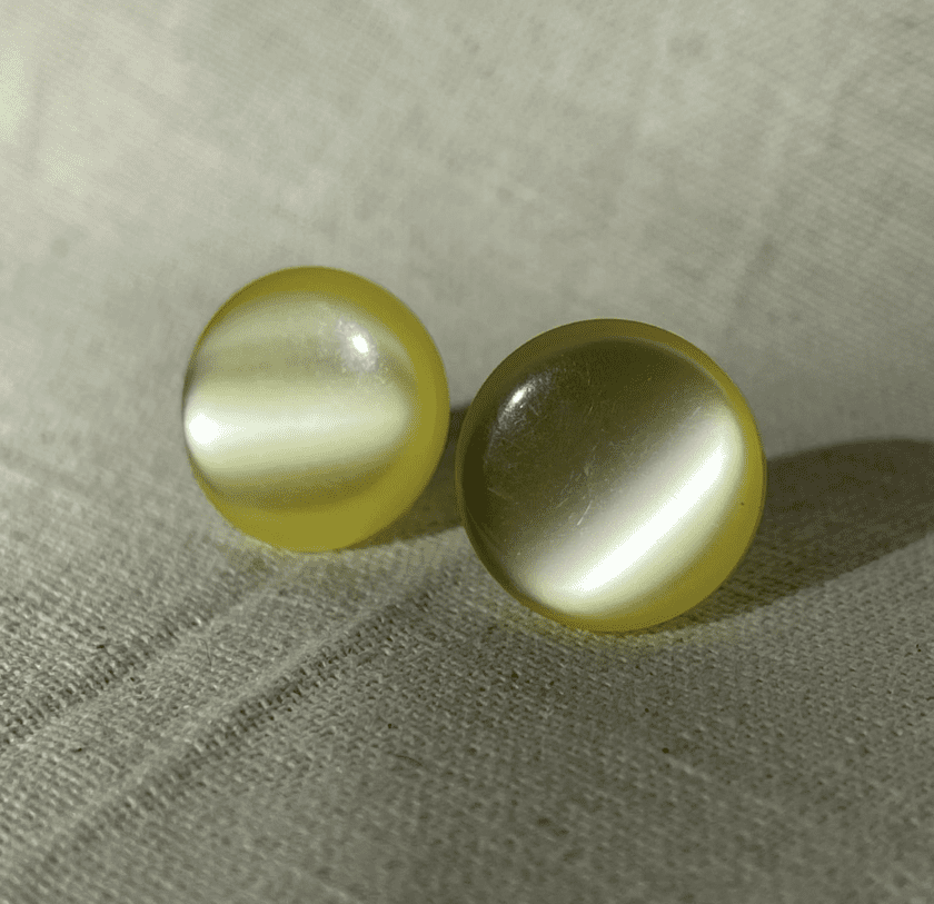 a pair of yellow pearls sitting on top of a white cloth.