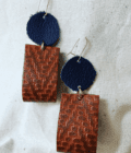 a pair of brown and blue earrings on a white surface.