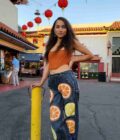a woman standing next to a pole with oranges on it.
