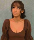 a woman wearing a brown top with a heart necklace.