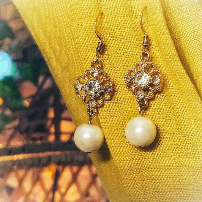 a pair of earrings sitting on top of a yellow cloth.