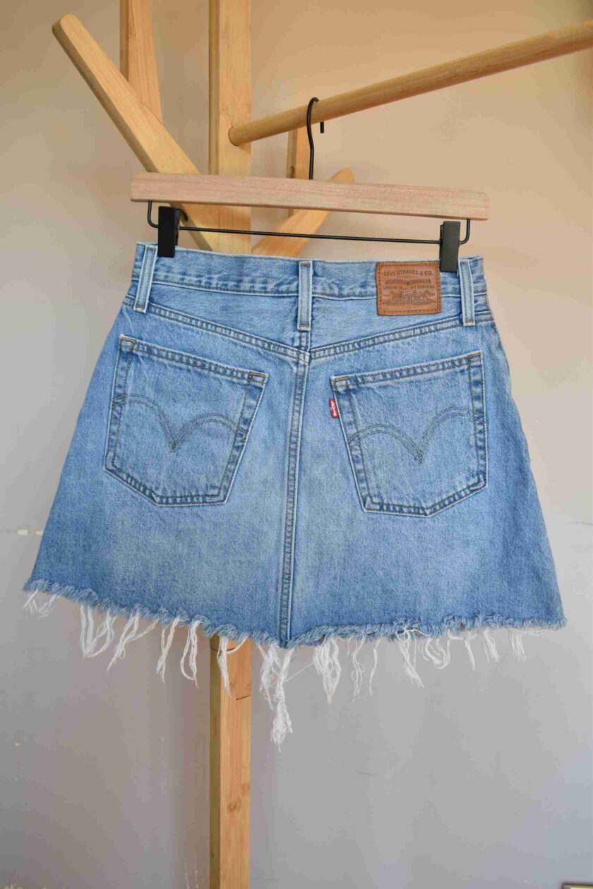 a denim skirt hanging on a clothes rack.