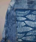 a blue jean jacket with white leaves on it.