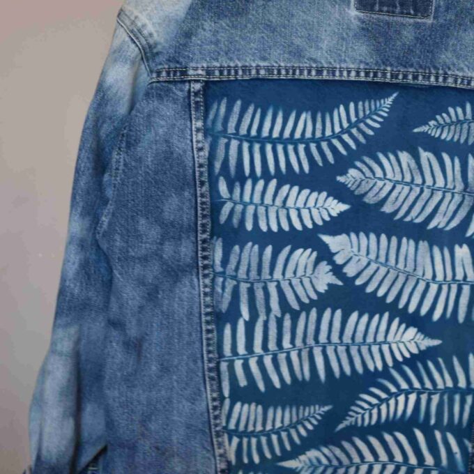 a blue jean jacket with white leaves on it.