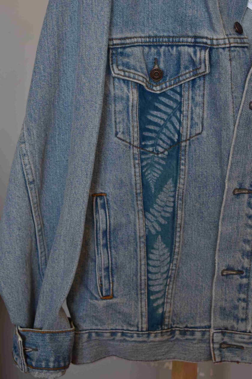 a denim jacket with a fern design on the back.